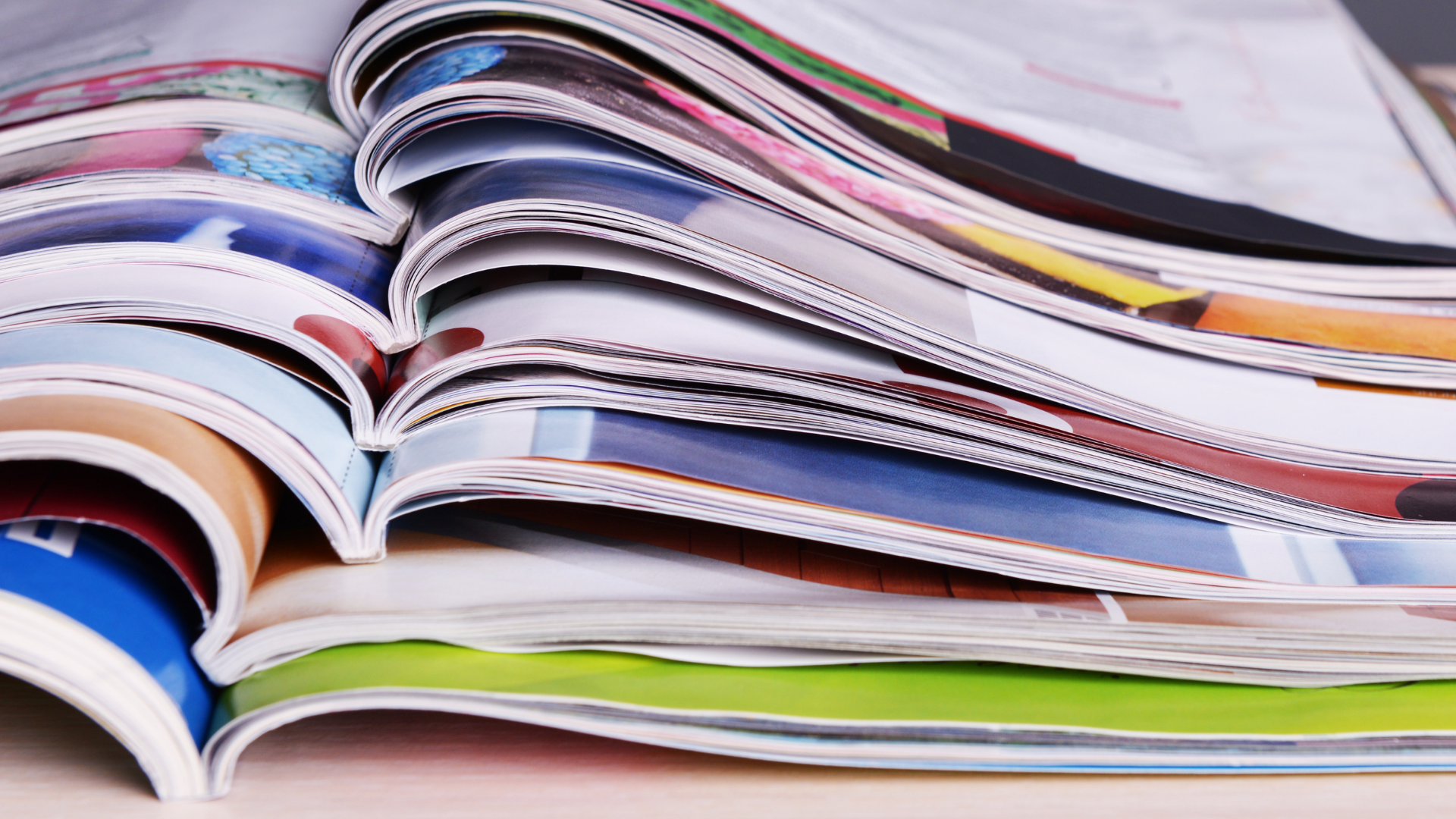 Close-up of a stack of colorful open magazines overlapping each other, showcasing various printed pages.
